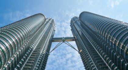 View of the iconic Petronas Twin Towers reaching towards a vibrant blue sky in Kuala Lumpur.