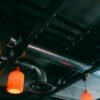 Low-angle view of a modern industrial ceiling featuring ducts and red lamps.
