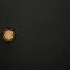 Minimalist image of a golden bottle cap on a dark surface, providing ample copy space.