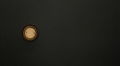 Minimalist image of a golden bottle cap on a dark surface, providing ample copy space.
