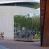 Contemporary architecture with reflective surfaces and passersby in Amsterdam.