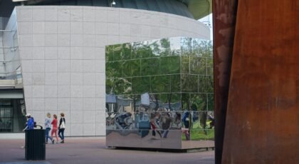 Contemporary architecture with reflective surfaces and passersby in Amsterdam.