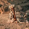 Close-up of a nautical rope tied to a rusty metal pole on a textured stone surface.