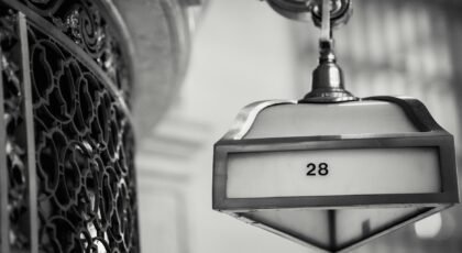 Black and white of metal lamp on stone wall near lattice in classic structure