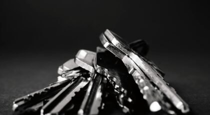 A close-up shot of a pile of metallic keys on a dark surface, emphasizing security and precision.