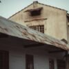 Aged building with a rusted metal roof, highlighting architectural decay.
