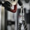 Close-up view of metal gym equipment attachment with rope and carabiner.