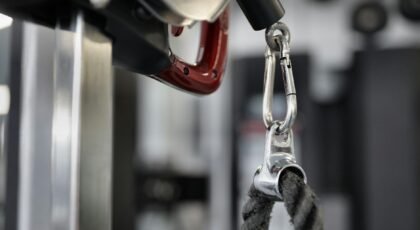 Close-up view of metal gym equipment attachment with rope and carabiner.