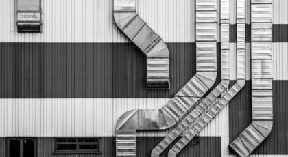 Monochrome image showcasing industrial ductwork and vents on a striped building exterior.