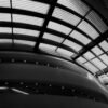 Black and white photo capturing a modern architectural ceiling with curved structural elements.