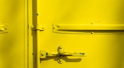 Close-up of a yellow metal door with a latch, highlighting industrial design and texture.