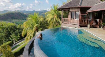 A woman relaxes in an infinity pool overlooking tropical scenery at a Bali villa.