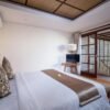 Elegant villa bedroom in Bali with wooden flooring and white linen.