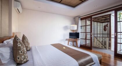 Elegant villa bedroom in Bali with wooden flooring and white linen.