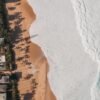 A breathtaking aerial photo of a beachfront in Hawaii with waves crashing onto the sandy shore.