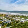 Aerial view of beachside villas with palm trees and ocean waves, perfect for travel and tourism.