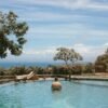 Man enjoying a serene resort pool with ocean view, perfect for relaxation and vacation vibes.