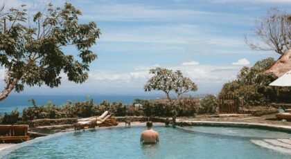 Man enjoying a serene resort pool with ocean view, perfect for relaxation and vacation vibes.