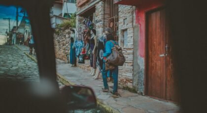 A quaint urban scene with a woman shopping on a cobblestone street by a boutique.