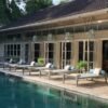 Chic poolside view at a luxury villa in Kuta, Bali with loungers and elegant architecture.