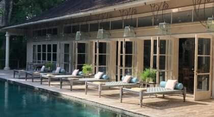Chic poolside view at a luxury villa in Kuta, Bali with loungers and elegant architecture.