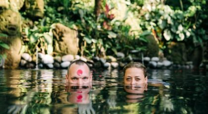 A man and woman submerged in a peaceful jungle pond, enjoying a moment of relaxation.