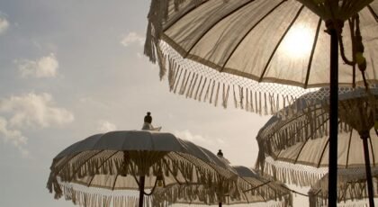 Traditional Balinese parasols with fringes creating shade on a sunny beach in Bali.