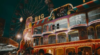 A lively scene at an amusement park with a ferris wheel and colorful lights at night.