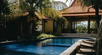 Relax by a luxurious tropical pool surrounded by lush palm trees under a sunny sky, perfect for summer getaways.