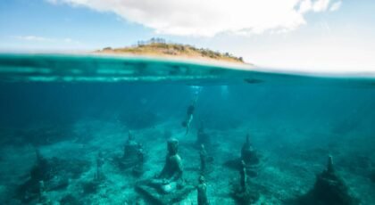 Explore serene underwater statues in clear turquoise waters.