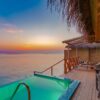 Peaceful overwater villa with private pool at sunset in the Maldives.