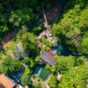 Experience the vibrant greenery and rustic architecture of a tropical resort in Cebu City from above.