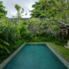 Luxurious villa pool surrounded by lush tropical greenery in Bali, Indonesia.