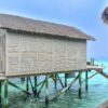 Scenic overwater bungalow with thatched roof set on the turquoise waters of the Maldives, a perfect tropical getaway.