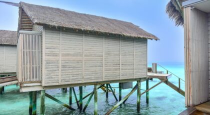 Scenic overwater bungalow with thatched roof set on the turquoise waters of the Maldives, a perfect tropical getaway.