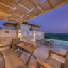 Cozy terrace with pergola overlooking mountains and infinity pool at sunset.
