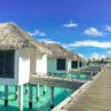 Scenic view of luxurious overwater bungalows on a sunny tropical day, ideal for travel and relaxation.