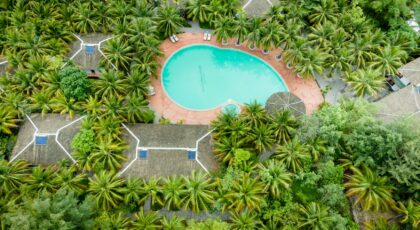 Stunning aerial shot of a resort with a swimming pool surrounded by lush palm trees.