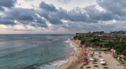 Stunning aerial view of a beach in Bali, Indonesia with visitors at sunset.