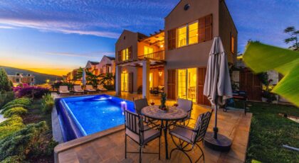 Charming holiday villa with illuminated pool at sunset, ideal for relaxation and luxury retreats.