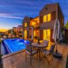 Charming holiday villa with illuminated pool at sunset, ideal for relaxation and luxury retreats.