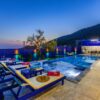 Elegant villa with a modern pool and deckchairs, perfect for a relaxing evening getaway.