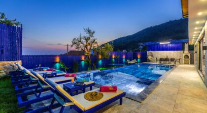 Elegant villa with a modern pool and deckchairs, perfect for a relaxing evening getaway.