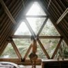 A person stands by a triangular bamboo window, embracing nature indoors.