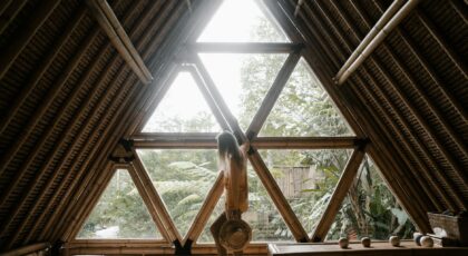 A person stands by a triangular bamboo window, embracing nature indoors.