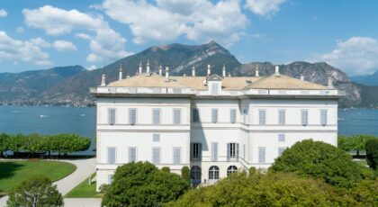 A grand villa surrounded by lush gardens and mountains near the Italian lake.