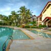Sunny tropical resort with pool and palm trees, ideal for vacation escape.