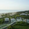 Scenic view of modern beachfront villas and lush greenery overlooking the ocean.