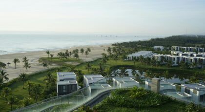 Scenic view of modern beachfront villas and lush greenery overlooking the ocean.