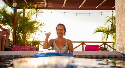 Smiling woman enjoying leisure time by a sunlit swimming pool in a villa.
